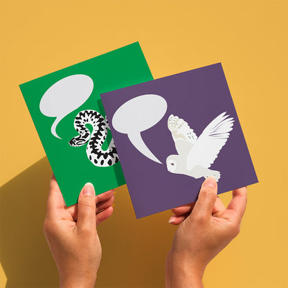 Two greeting card held against a yellow backgroun. Front card is the purple card with barn owl illustration, back card is the green card with adder illustration.