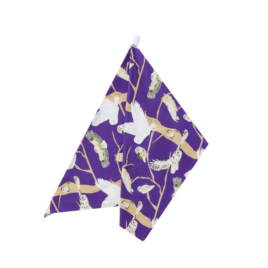 Purple towel with owls, bird pattern shown hanging on a white background