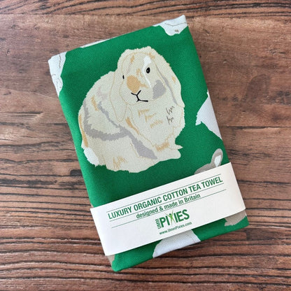 Bright Green Rabbits design organic cotton tea towel on a wooden table top