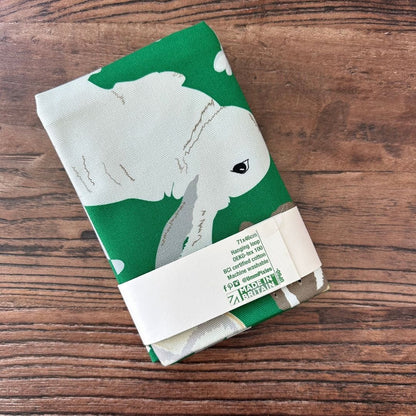 Bright Green Rabbits design organic cotton tea towel on a wooden table top
