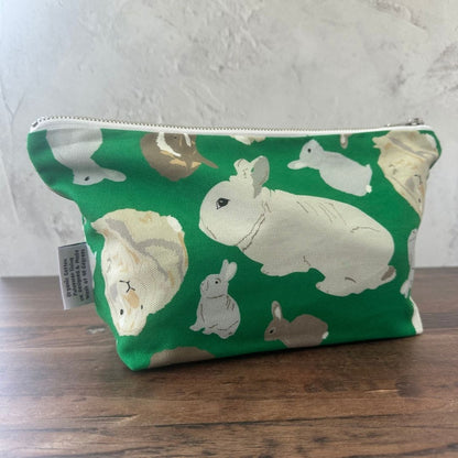 Green pouch with rabbit pattern on a wooden surface