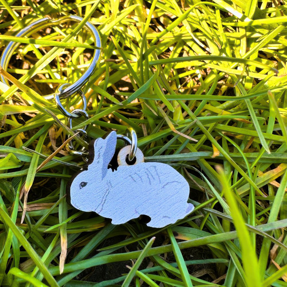 Rabbit key chain shown lying in grass on a sunny day