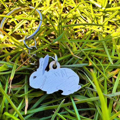 Rabbit key chain shown lying in grass on a sunny day