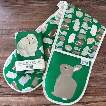 Bright Green Rabbits design organic cotton Oven Mitts shown with matching tea towel on a wooden counter