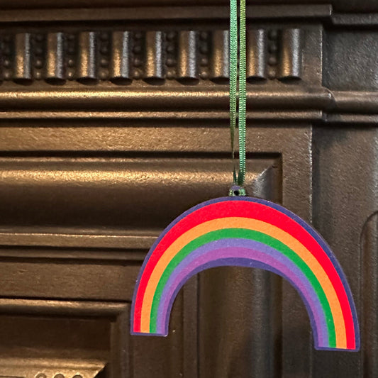 Rainbow-shaped wooden hanging decoration shown hanging from a matelpiece