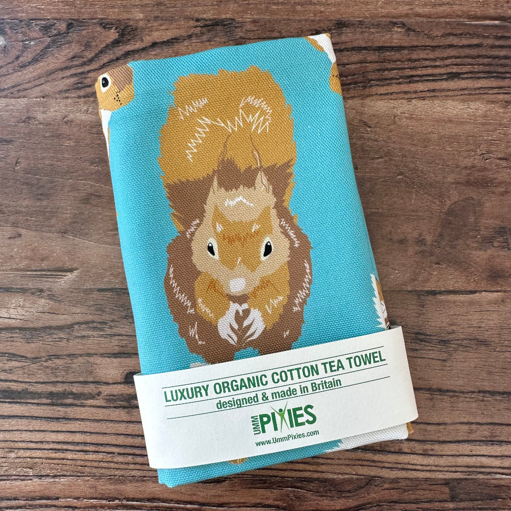 Tea towel with red squirrel design on a wooden surface