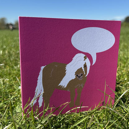 Pink Greetings Card with Shetland Pony illustration and speech bubble to add personalisation shown standing in a grassy area of a large park on a sunny day
