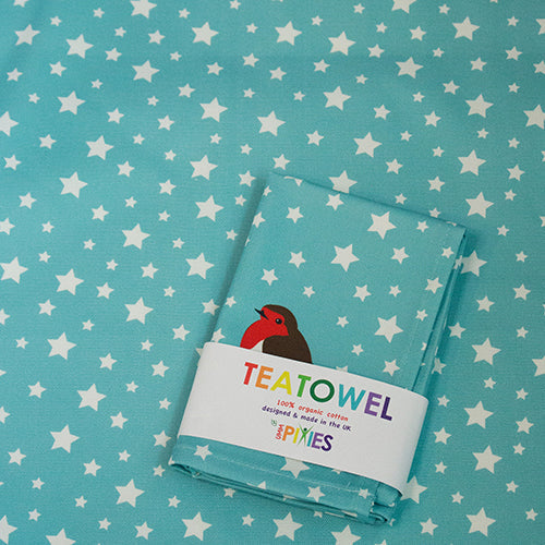 Organic Cotton tea towel shown in recyclable packaging laid on and Robin and Stars tea towel design