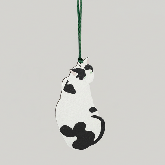 Decorative cat-shaped ornament on a green string against a light gray background