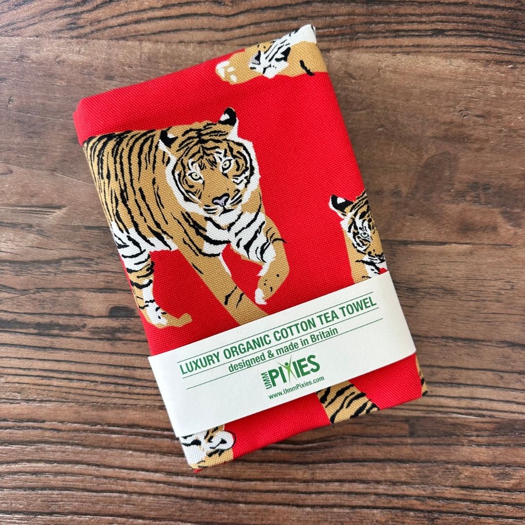 Bright red Tigers design organic cotton tea towel shown on a wooden table