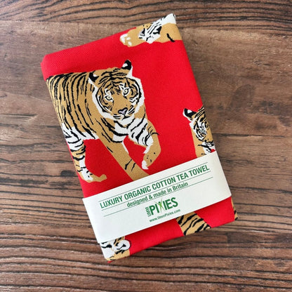 Bright red Tigers design organic cotton tea towel shown on a wooden table