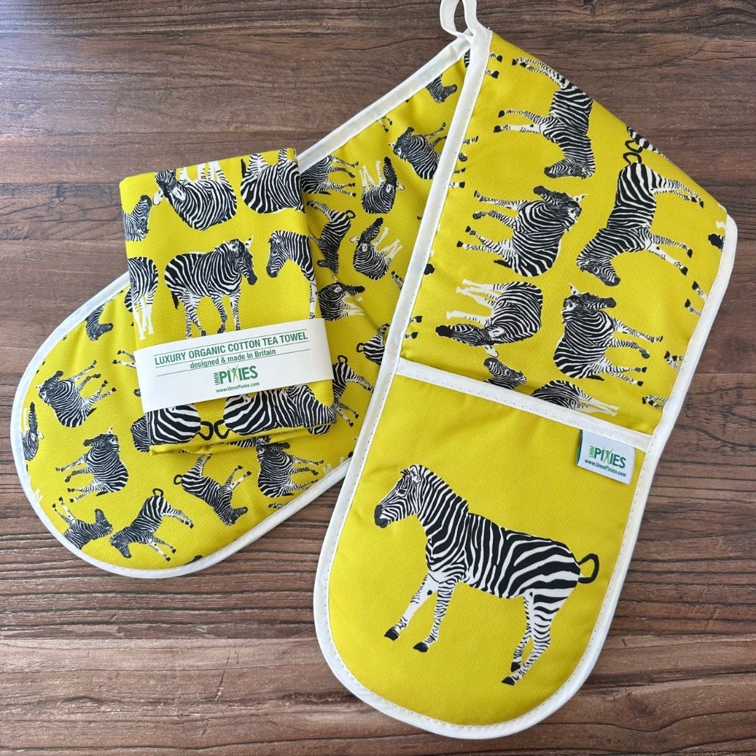 Bright yellow Zebra design oven gloves  and matching tea towel on wooden surface