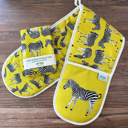 Bright yellow Zebra design oven gloves  and matching tea towel on wooden surface
