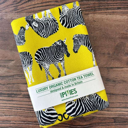 Bright yellow Zebra design tea towel on a wooden table