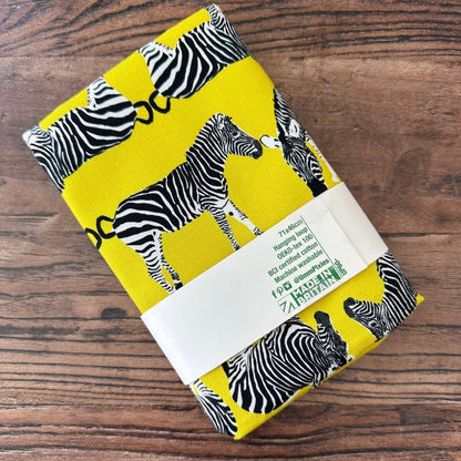 Bright yellow Zebra design tea towel on wooden surface