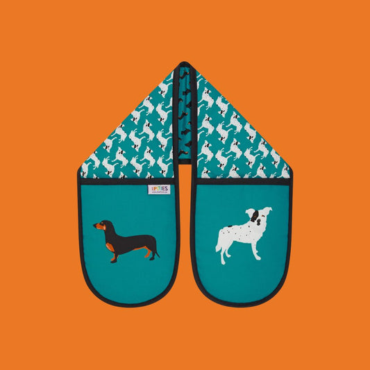 Bright petrol blue organic cotton oven mitts with illustrative dog design featuring dacshunds, scottish terriers and CC the wonder dog. Shown here on a plain orange background