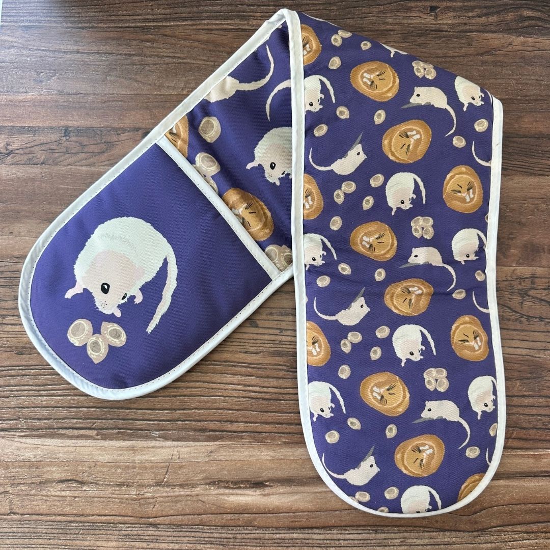 Rich Purple Hazel Dormouse design organic cotton Oven Mitts shown with inside print uppermost on a wooden counter
