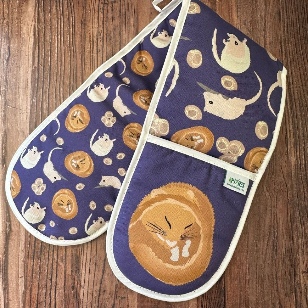 Rich Purple Hazel Dormouse design organic cotton Oven Mitts shown  on a wooden counter
