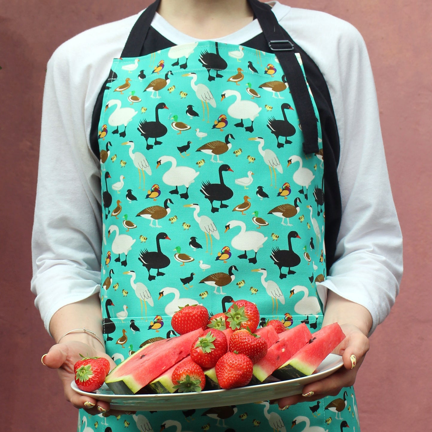 Ducks Design Organic Cotton Apron shown worn by model holding platter of fruit