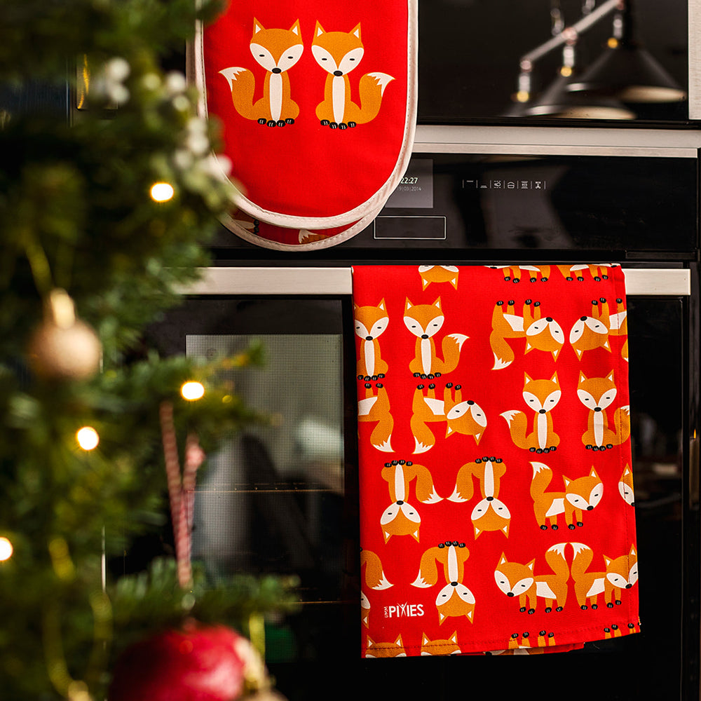 Red Fox Oven Gloves and coordinating Tea towel  in Organic Cotton  shown hanging on oven door