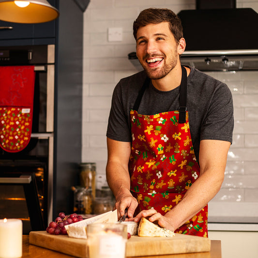 Gingerbread Design Organic Cotton Apron shown as worn by male model with coordinating oven gloves in the background