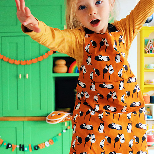Orange Black and White Cats Design Organic Cotton Apron, model wears younger child size, photo credit:  @Rachelandthelittlebirds